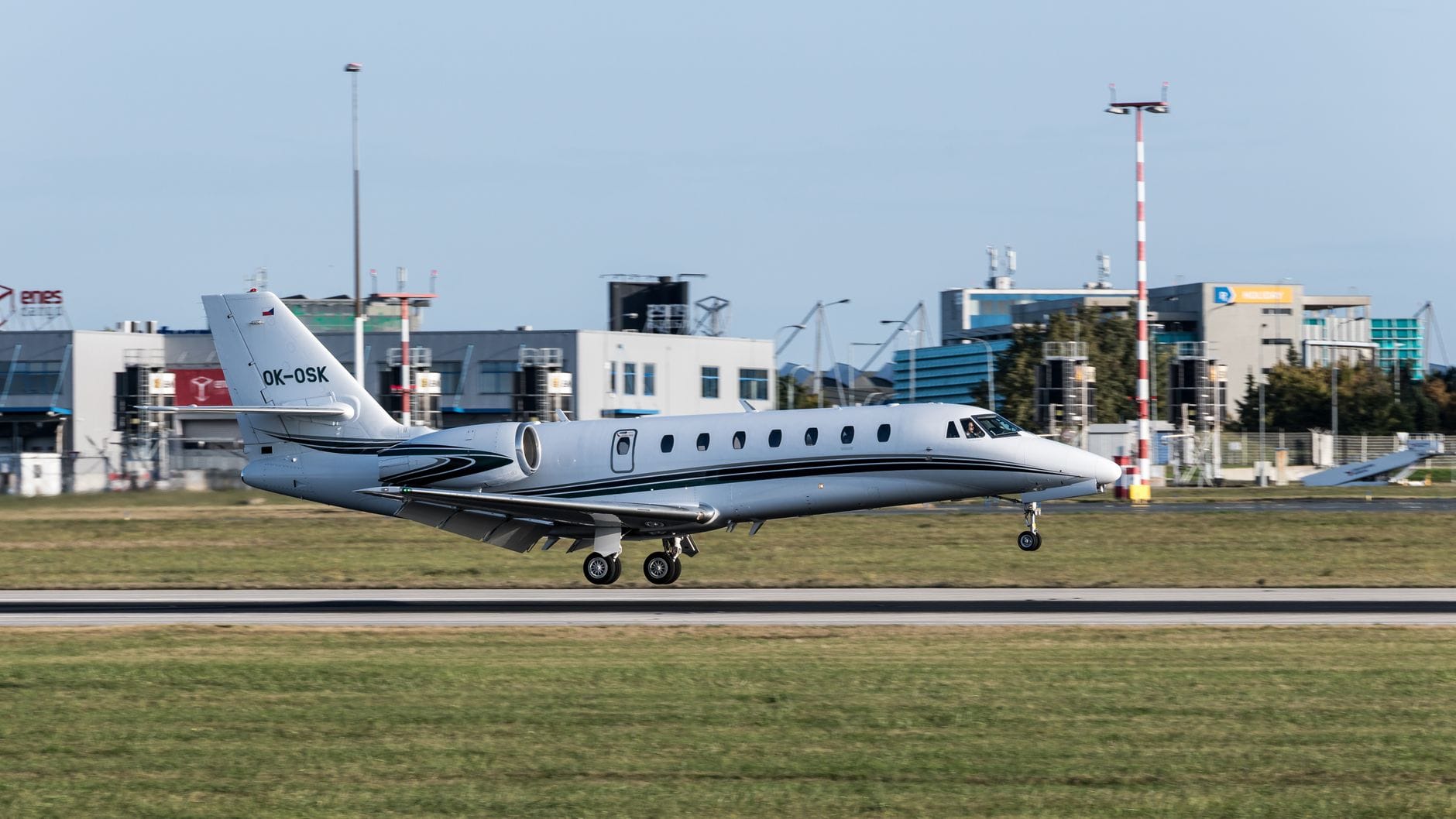Privatjet landet an einem Flughafen mit modernen Terminalgebäuden im Hintergrund an einem sonnigen Tag