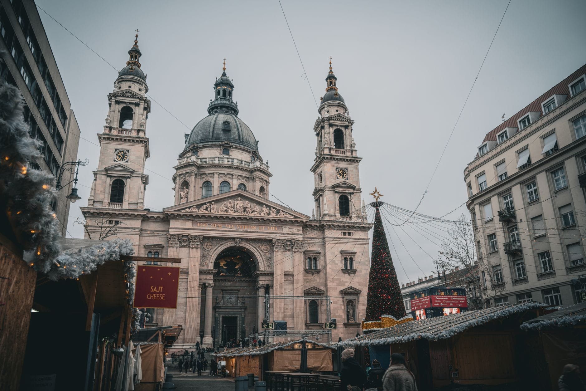 Stephansbasilika in Budapest mit Weihnachtsmarktständen und einem geschmückten Baum im Vordergrund während der winterlichen Festtagssaison