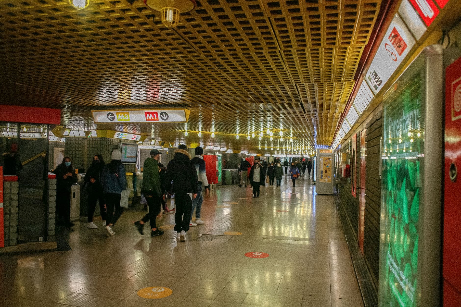 Menschenmassen, die durch die U-Bahnstation Széchenyi gehen, mit gut sichtbaren Schildern für die Budapester U-Bahnlinie M1.