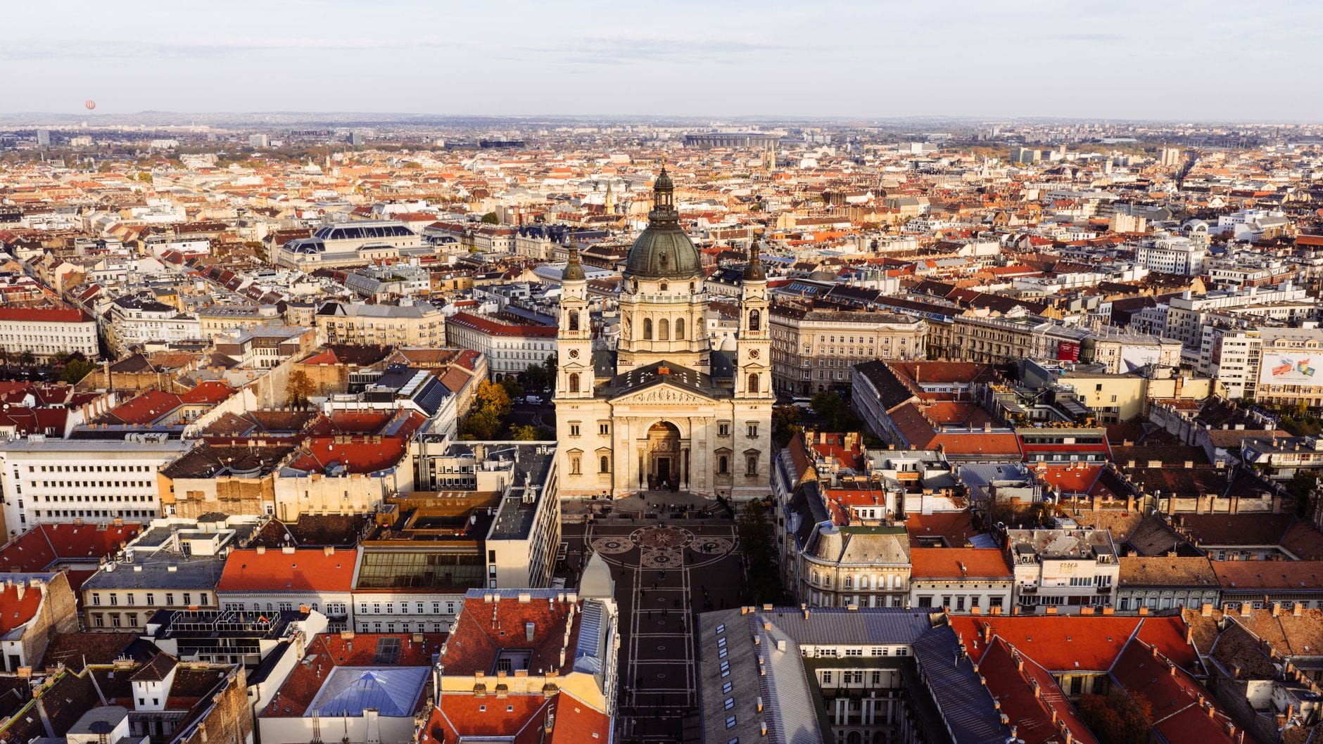 Vista aerea della cupola della Basilica di Santo Stefano che si erge sopra il lato Pest di Budapest, circondata dai tetti della città e da ampi panorami urbani.