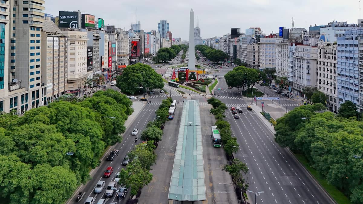 มุมมองทางอากาศของ Avenida 9 de Julio อันกว้างใหญ่ในบัวโนสไอเรส พร้อม Obelisco อันโด่งดังใจกลางเมือง ล้อมรอบด้วยพืชพรรณและชีวิตเมืองที่คึกคัก