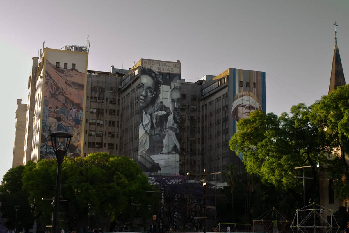 อาคารในบัวโนสไอเรสที่มีภาพจิตรกรรมฝาผนังขนาดใหญ่แสดงภาพของ Eva Perón และเหตุการณ์ที่เกี่ยวข้องกับมรดกของเธอ ล้อมรอบด้วยต้นไม้และทิวทัศน์เมือง