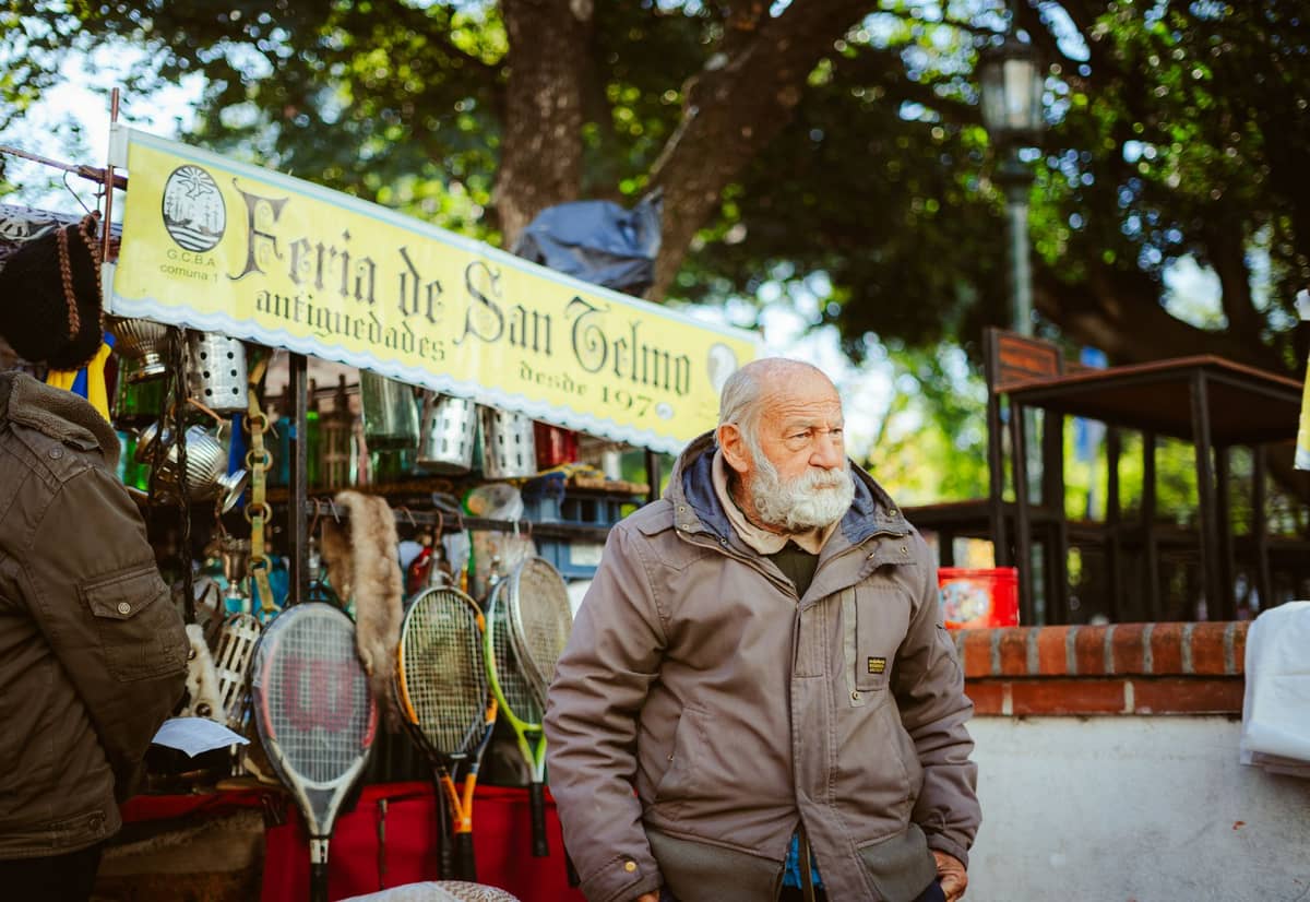 พ่อค้าแม่ค้าริมถนนที่ตลาดของเก่า Feria de San Telmo พร้อมป้ายและสินค้าต่างๆ ที่จัดแสดงในบรรยากาศกลางแจ้งที่คึกคัก.