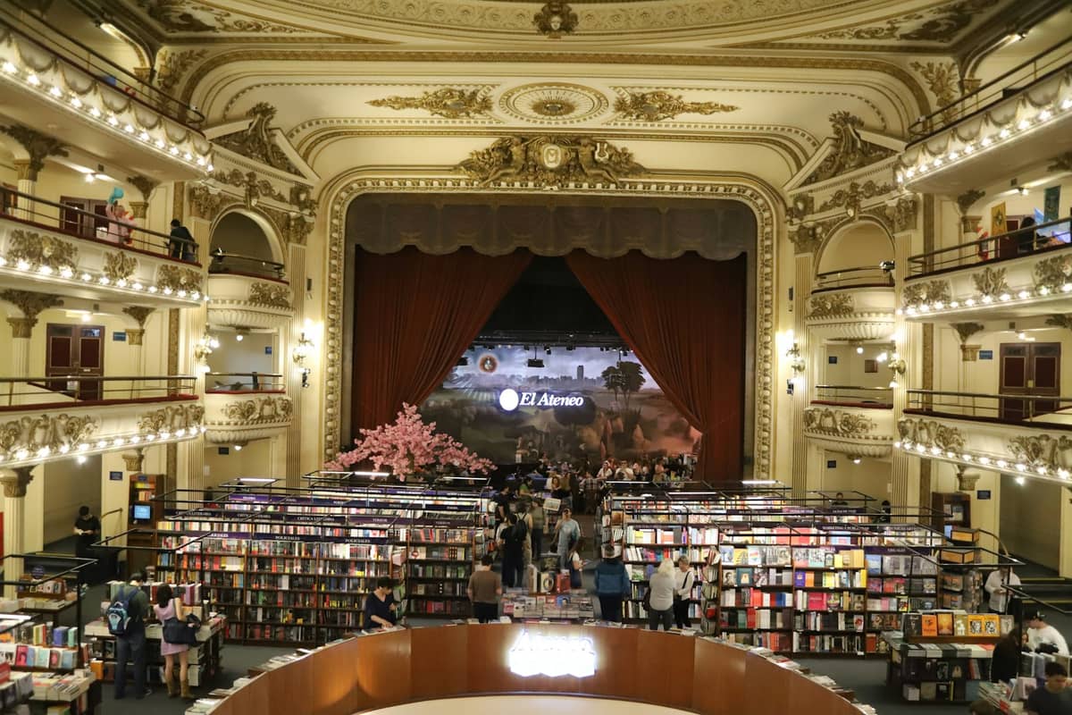 มุมมองภายในกว้างของร้านหนังสือ El Ateneo Grand Splendid ในบัวโนสไอเรส แสดงให้เห็นระเบียงโรงละครเดิม เพดานประดับประดา และชั้นวางหนังสือที่เต็มไปด้วยผู้เยี่ยมชม