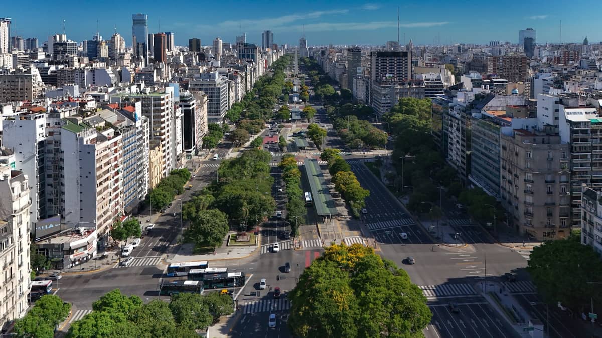 มุมสูงถ่ายกว้าง ถ. Avenida 9 de Julio กับวิวเมืองบัวโนสไอเรส ถนนใหญ่ ต้นไม้ สีเขียว และย่านต่างๆ ในเมือง ท้องฟ้าโปร่งสดใส
