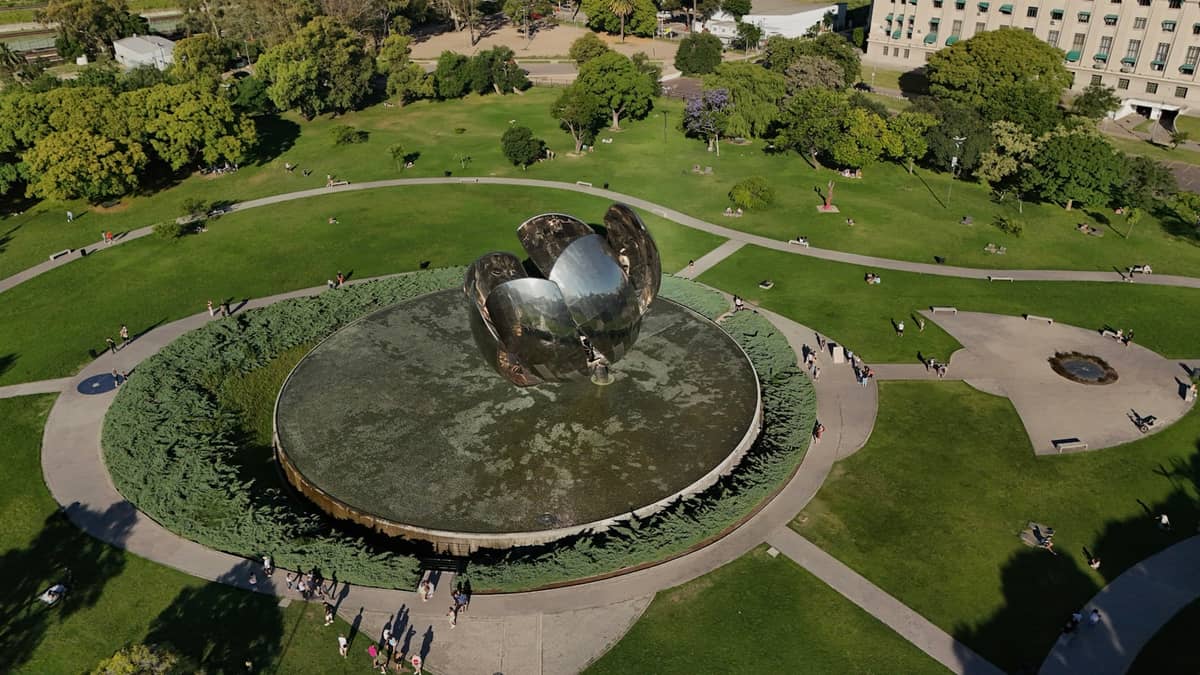 มุมมองทางอากาศของ Floralis Genérica ประติมากรรมดอกไม้สแตนเลสชื่อดังในสวนสาธารณะแห่งหนึ่งใน Buenos Aires ล้อมรอบด้วยทางเดิน ต้นไม้ และสนามหญ้าสีเขียว