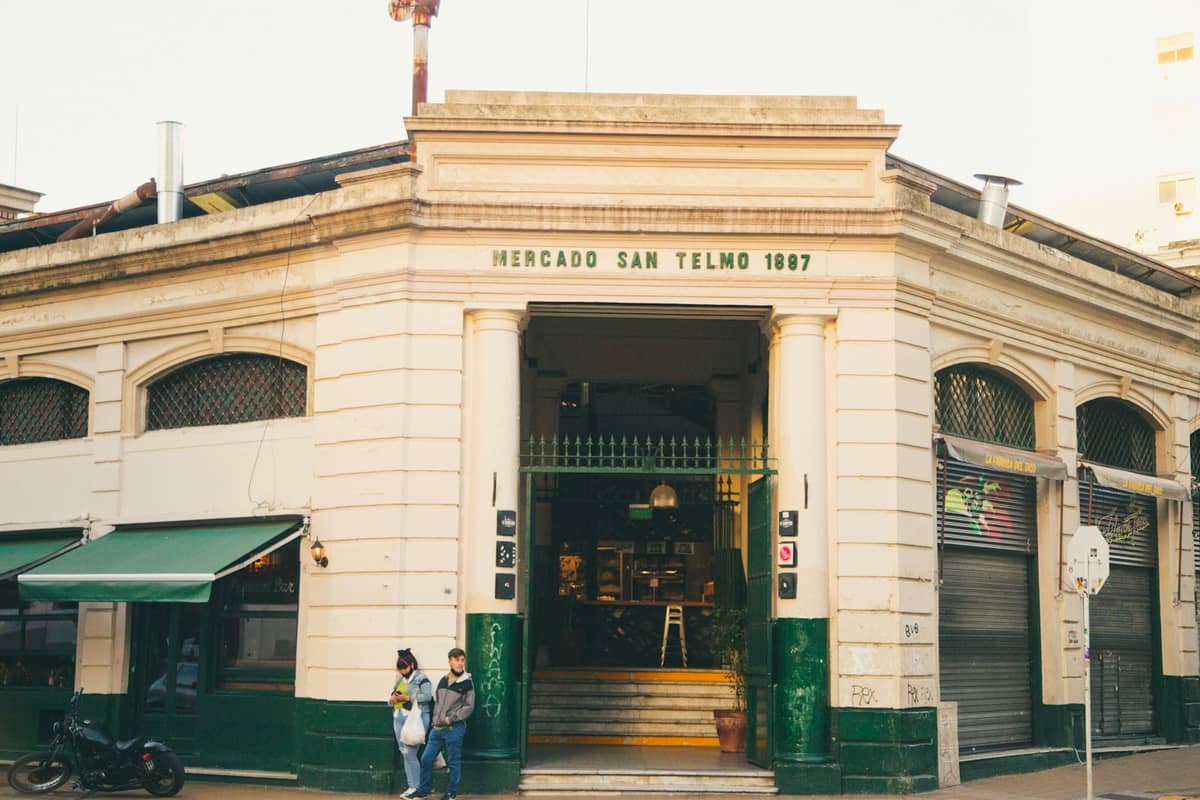 ด้านหน้าของ Mercado San Telmo พร้อมป้ายปี 1897 บันไดทางเข้า และผู้คนยืนอยู่ด้านนอกในบัวโนสไอเรส