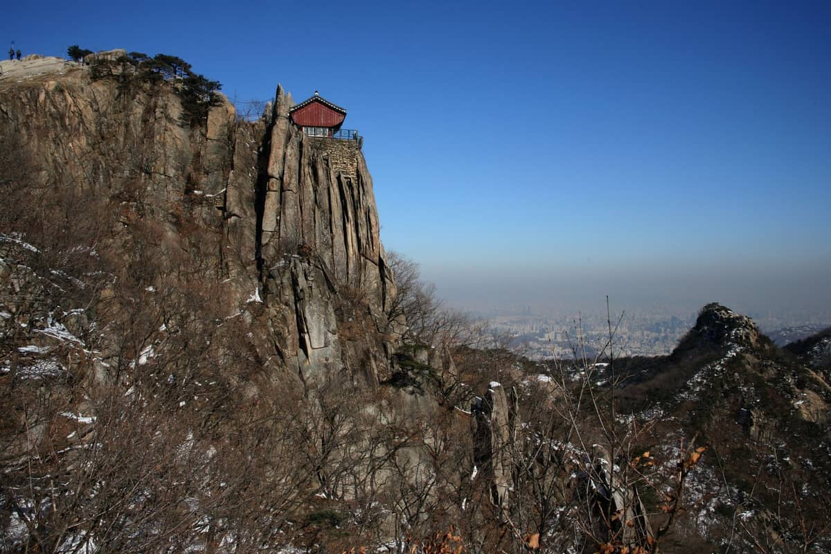Trilha rochosa até o cume no Parque Nacional Bukhansan com um pavilhão na falésia e vistas panorâmicas em direção à cidade de Seul.
