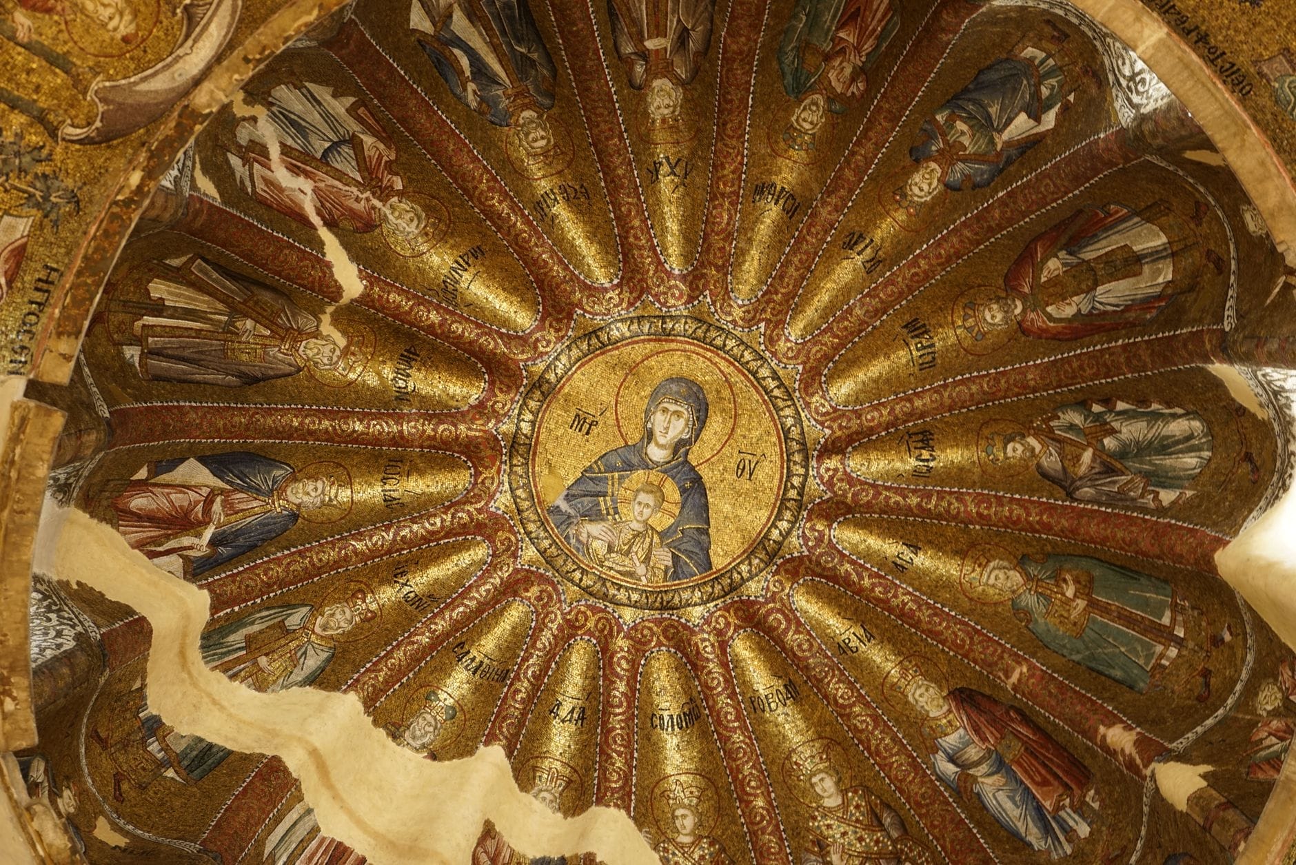 Mosaico dorato di una cupola bizantina raffigurante la Vergine Maria con il Bambino, circondati da santi, esempio raffinato dell'arte cristiana nell'interno di una chiesa.