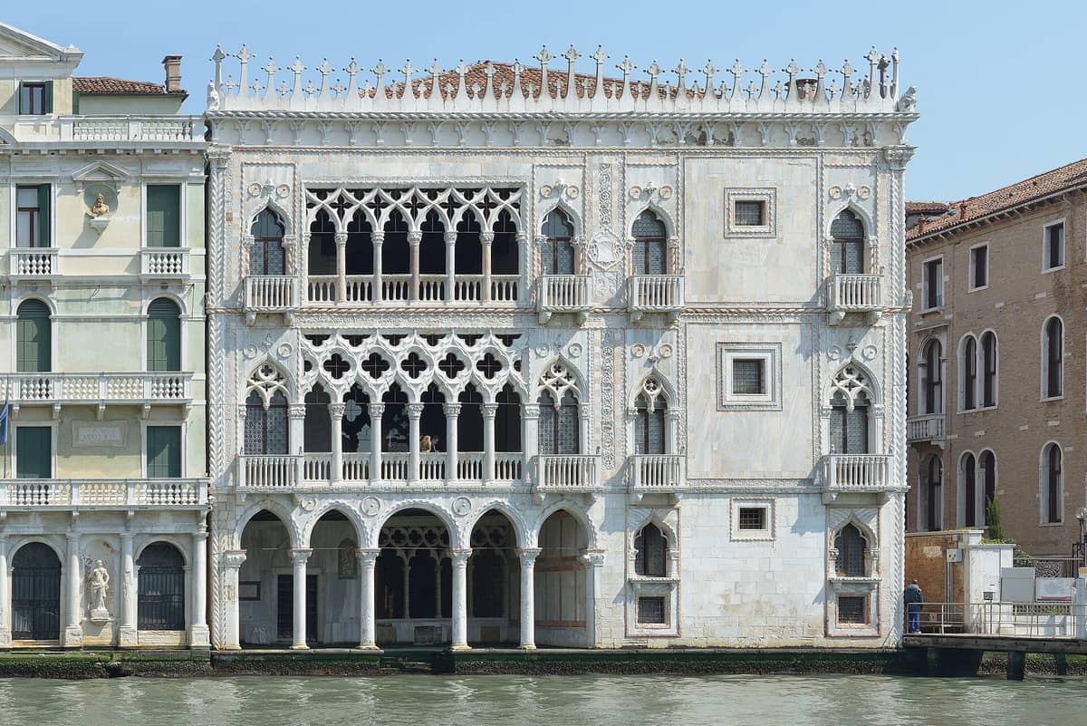 Frontansicht des Palastes Ca' d'Oro in Venedig mit seiner reich verzierten gotischen Fassade direkt am Canal Grande unter klarem blauen Himmel.