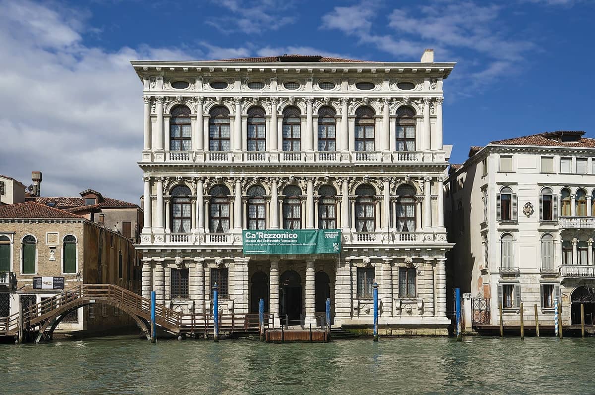 Vorderansicht des Ca' Rezzonico, eines prächtigen Palazzo aus dem 18. Jahrhundert, mit detaillierten Steinbögen und Balkonen mit Blick auf den Canal Grande in Venedig.