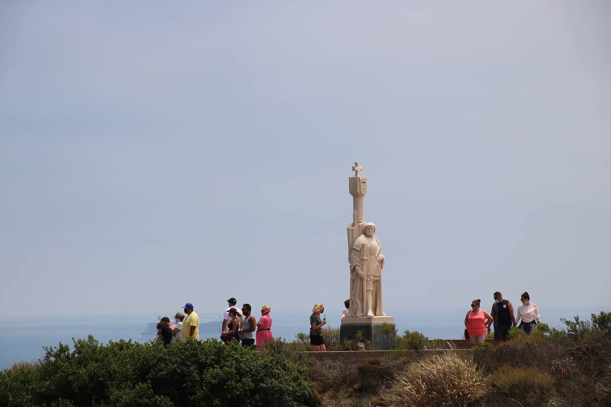 Besucher stehen bei der markanten Cabrillo-Statue im Cabrillo National Monument mit Meeresblick und weitem Himmel im Hintergrund.