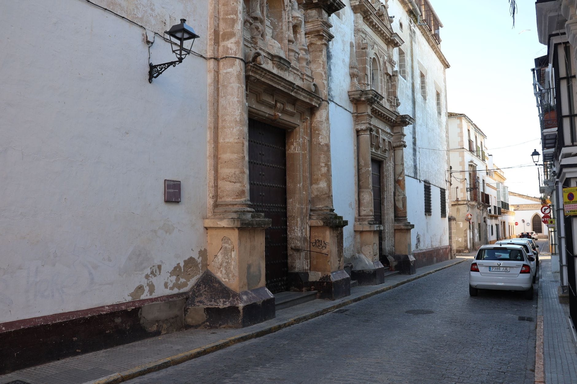 Cádiz eski şehrinde tarihi taş cepheler, süslü kapı girişi ve klasik demir sokak lambası olan dar bir sokak.