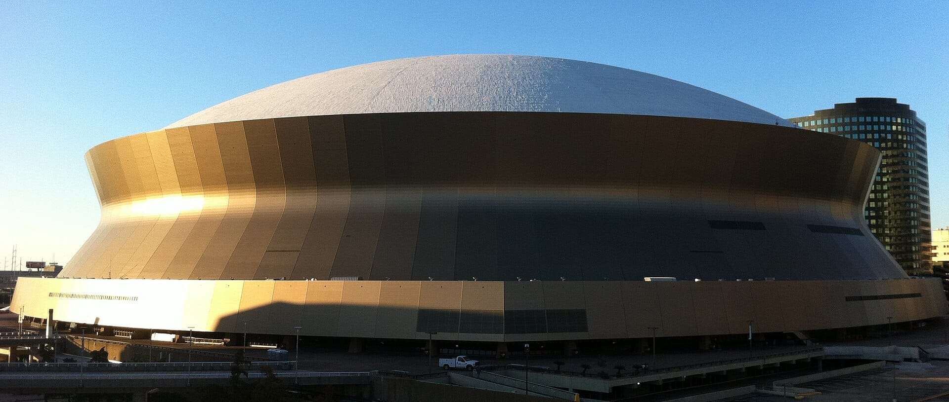 L'iconico esterno dorato del Caesars Superdome a New Orleans, fotografato sotto un cielo azzurro limpido con gli edifici della città sullo sfondo.