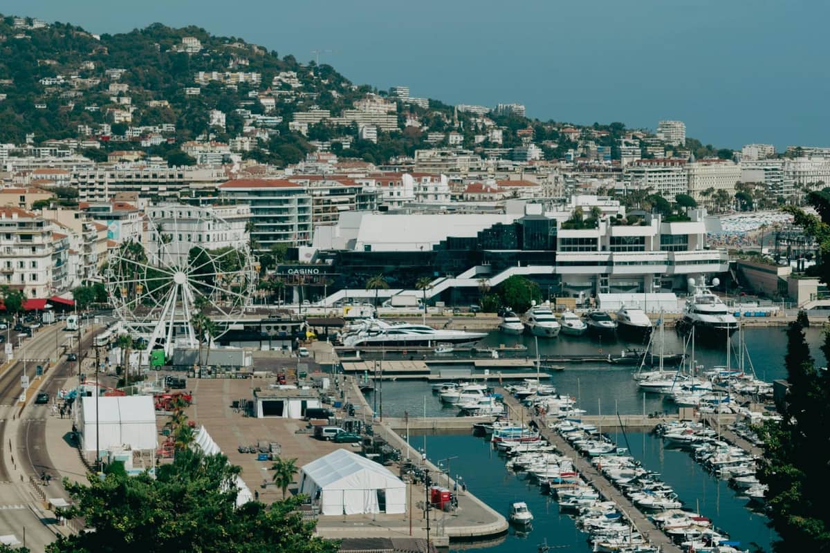 Panoramablick auf Cannes mit dem Yachthafen, der Uferpromenade, den Hügeln und den Stadtgebäuden unter einem klaren Himmel.