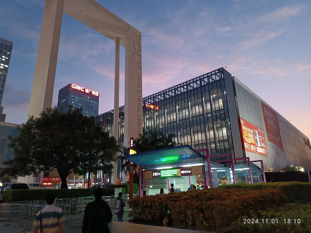 Evening view outside a modern Guangzhou building with World Trade Center arch, GIMC tower, and metro entrance visible.