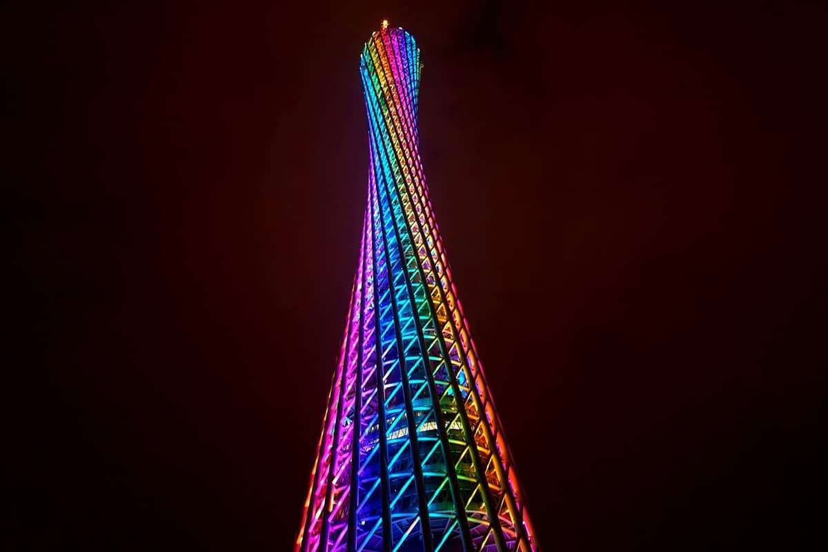 Canton Tower lit up in vibrant rainbow colors at night, against a dark sky in Guangzhou’s cityscape.