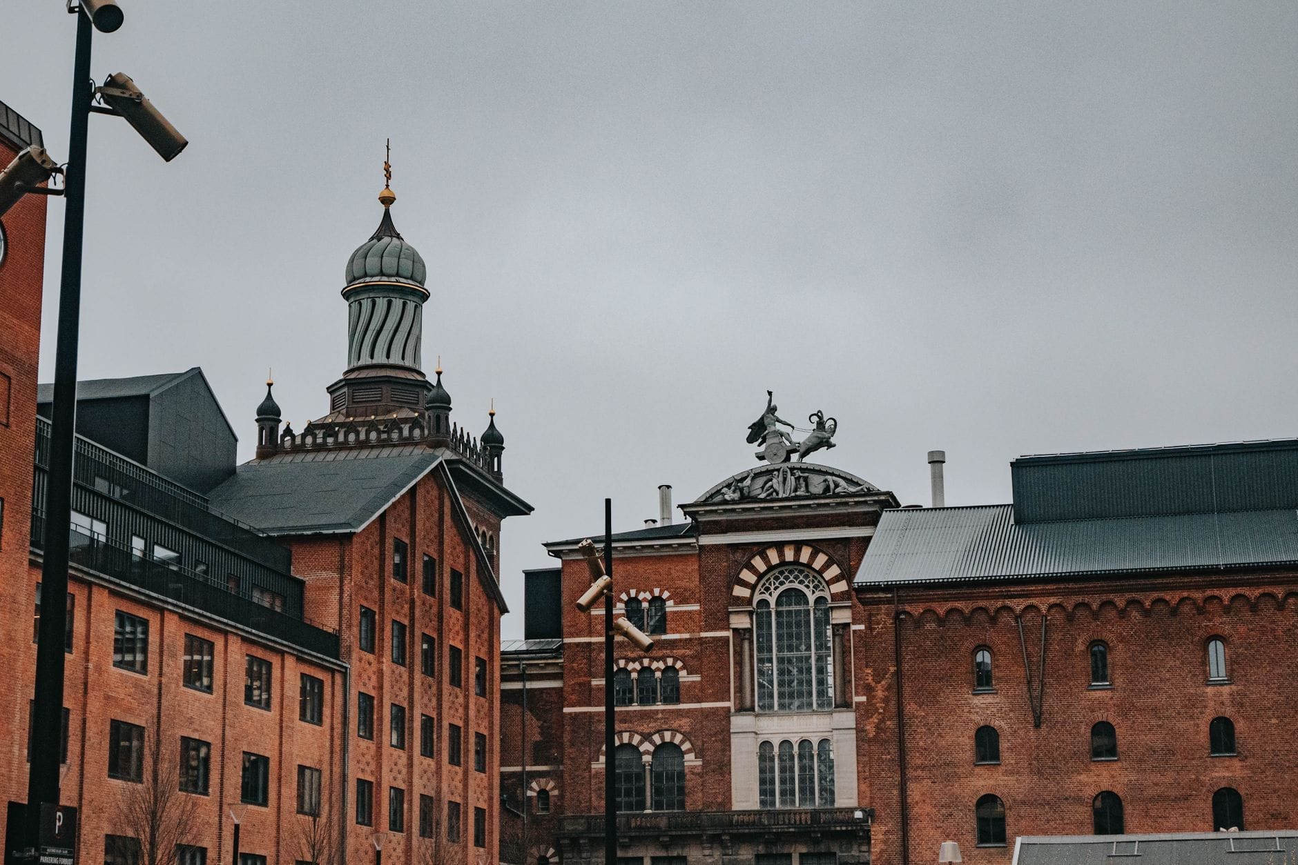 Edifici storici in mattoni rossi nel Carlsberg District, con dettagli architettonici distintivi e un cielo nuvoloso tipico di Copenaghen.