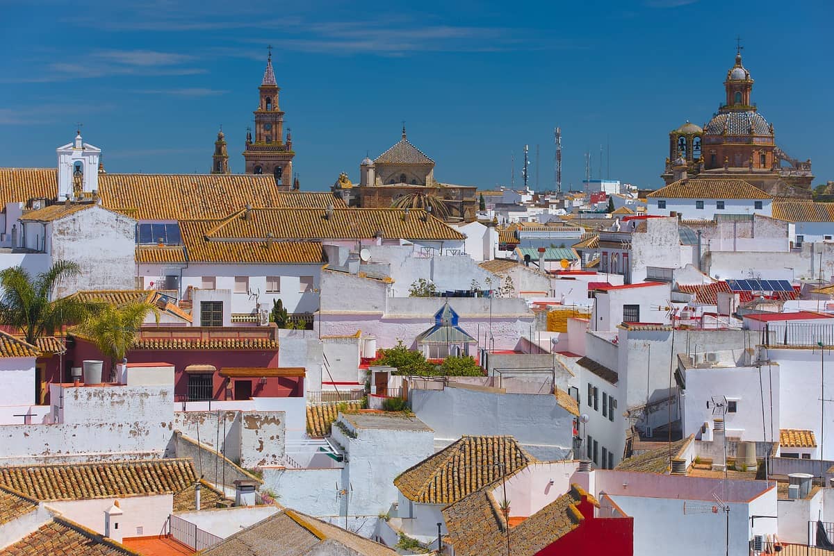วิวพาโนรามาของใจกลางเมืองประวัติศาสตร์ของ Carmona พร้อมบ้านฉาบปูนสีขาว หลังคาดินเผา และหอระฆังโบสถ์อันโดดเด่นใต้ท้องฟ้าสีฟ้าแจ่มใส