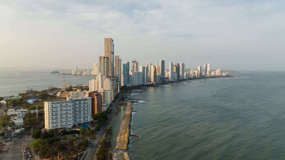 A wide aerial view of Cartagena’s urban beachfront with high-rise buildings lining the shore and calm Caribbean waters, showcasing the city’s main beach area.