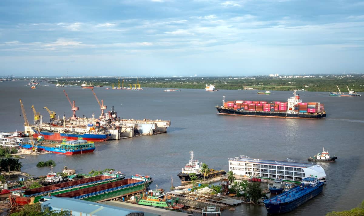 Wide view of a bustling industrial port with container ships, cranes, and various vessels docked along the Cartagena waterfront.