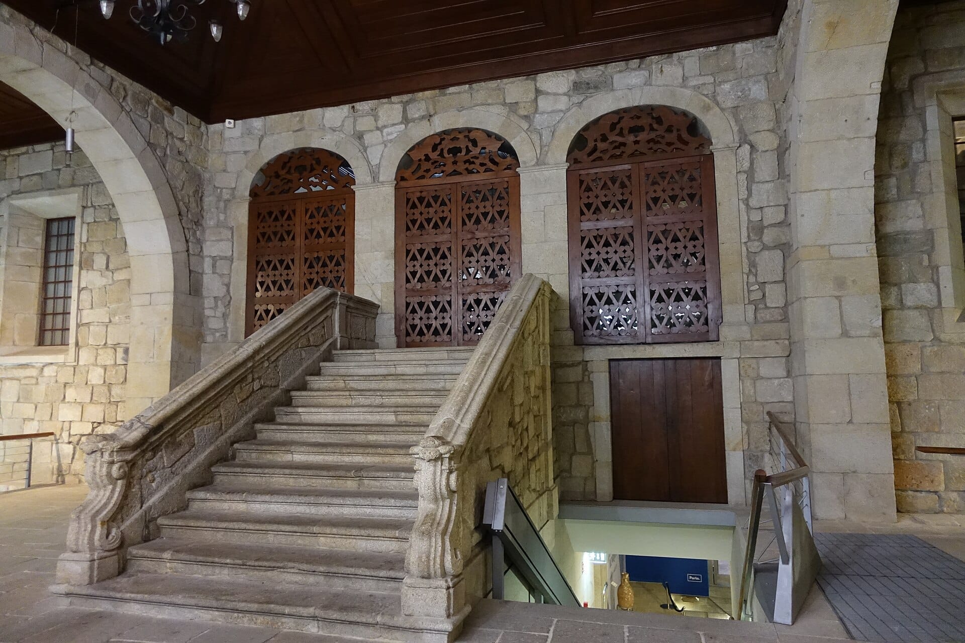Scalinata in pietra e finestre ad arco con reticolo in legno all'interno della Casa do Infante, che mostra l'architettura storica dell'edificio civico più antico di Porto.