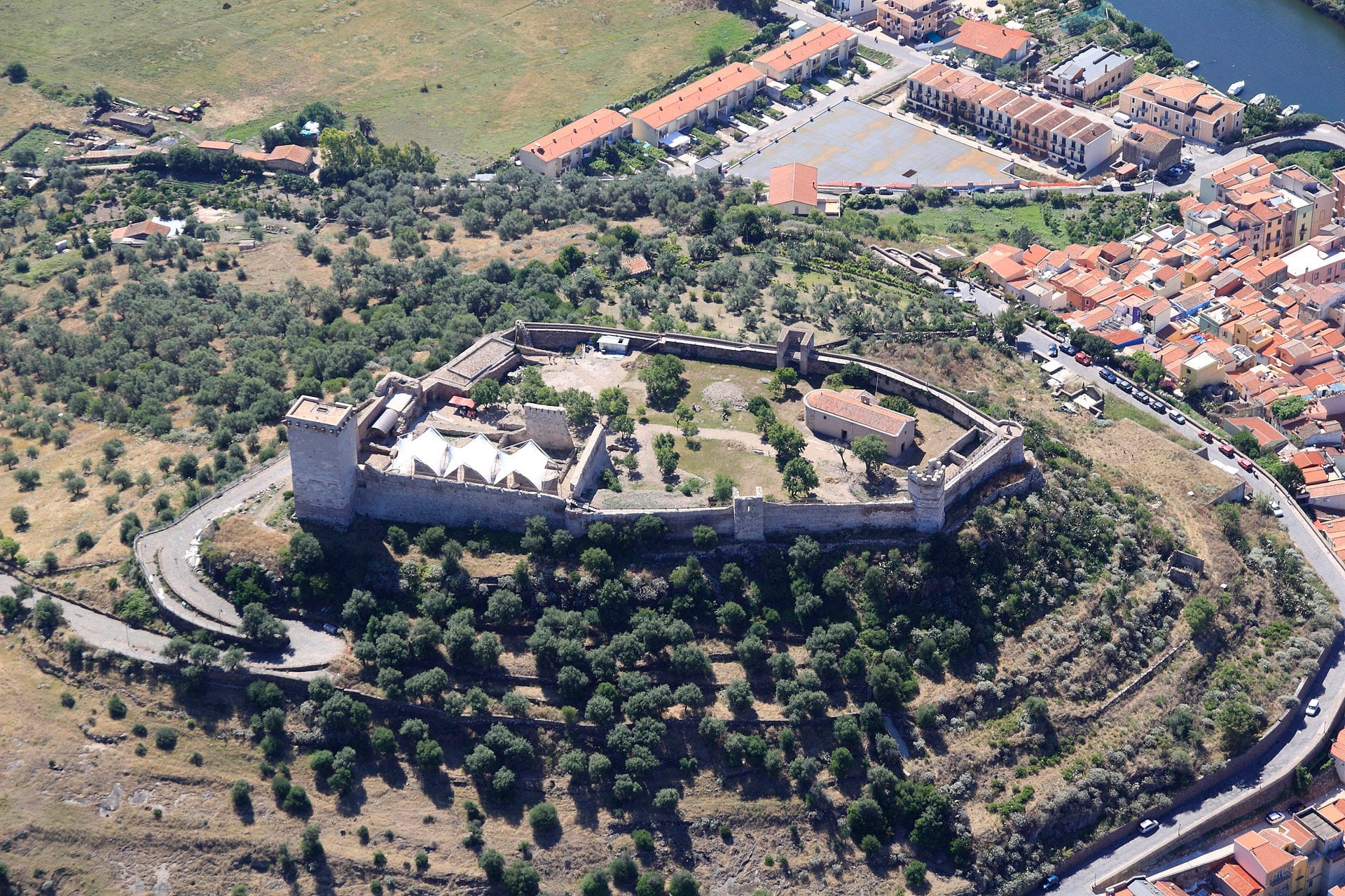 Luftaufnahme des Castello Malaspina, einer mittelalterlichen Festung auf dem Hügel Serravalle, umgeben von grüner Landschaft und mit Blick auf die bunte Stadt Bosa.