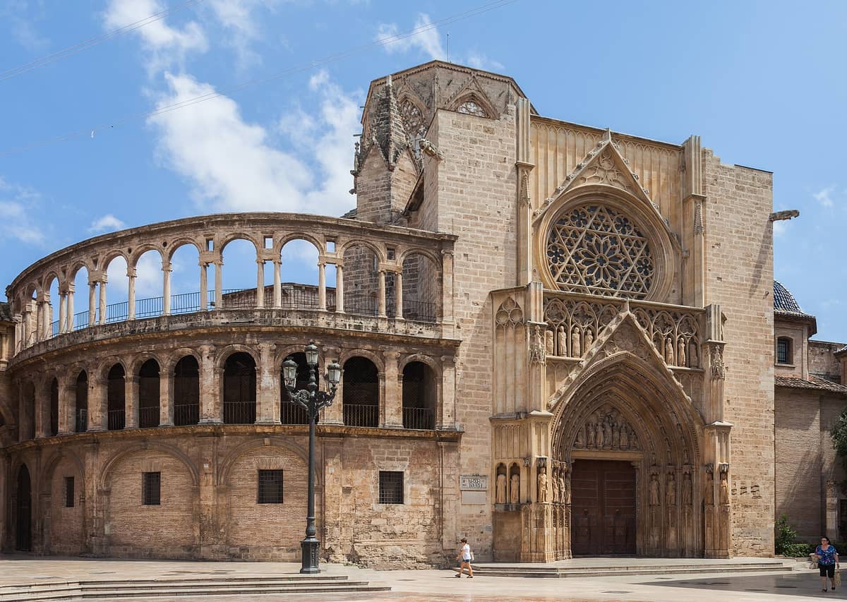 Vista esterna della Cattedrale di Valencia con il portale gotico principale e la caratteristica torre ottagonale su Plaza de la Virgen, fotografata di giorno con cielo azzurro sullo sfondo.