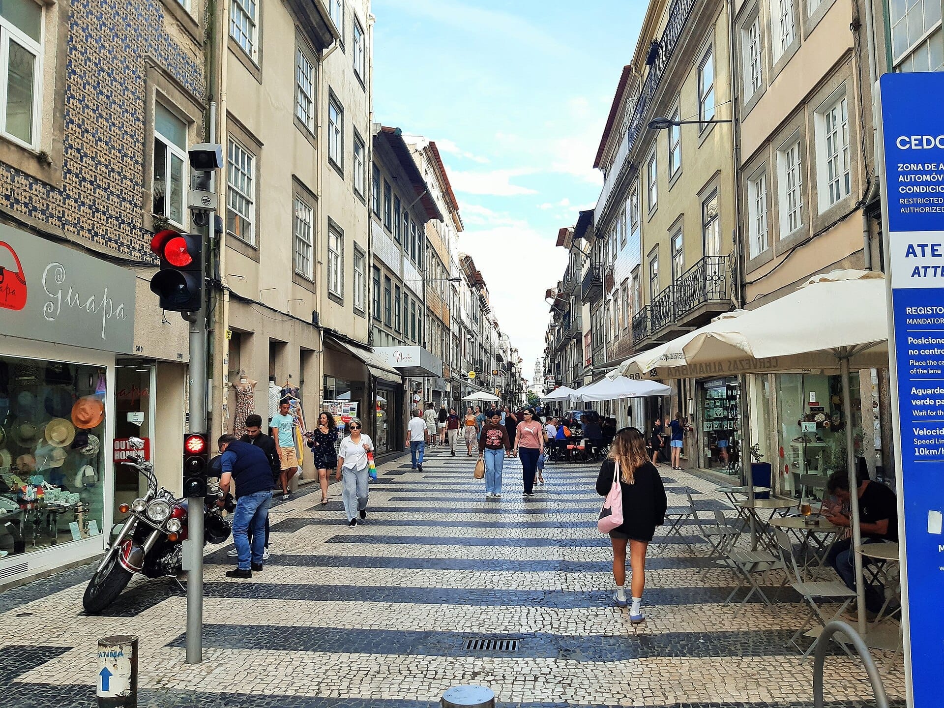ถนนคนเดินในย่าน Cedofeita เมือง Porto พร้อมผู้คนที่เดินผ่านระหว่างอาคารประวัติศาสตร์ ร้านค้าอิสระ และคาเฟ่กลางแจ้งในวันที่แดดสดใส
