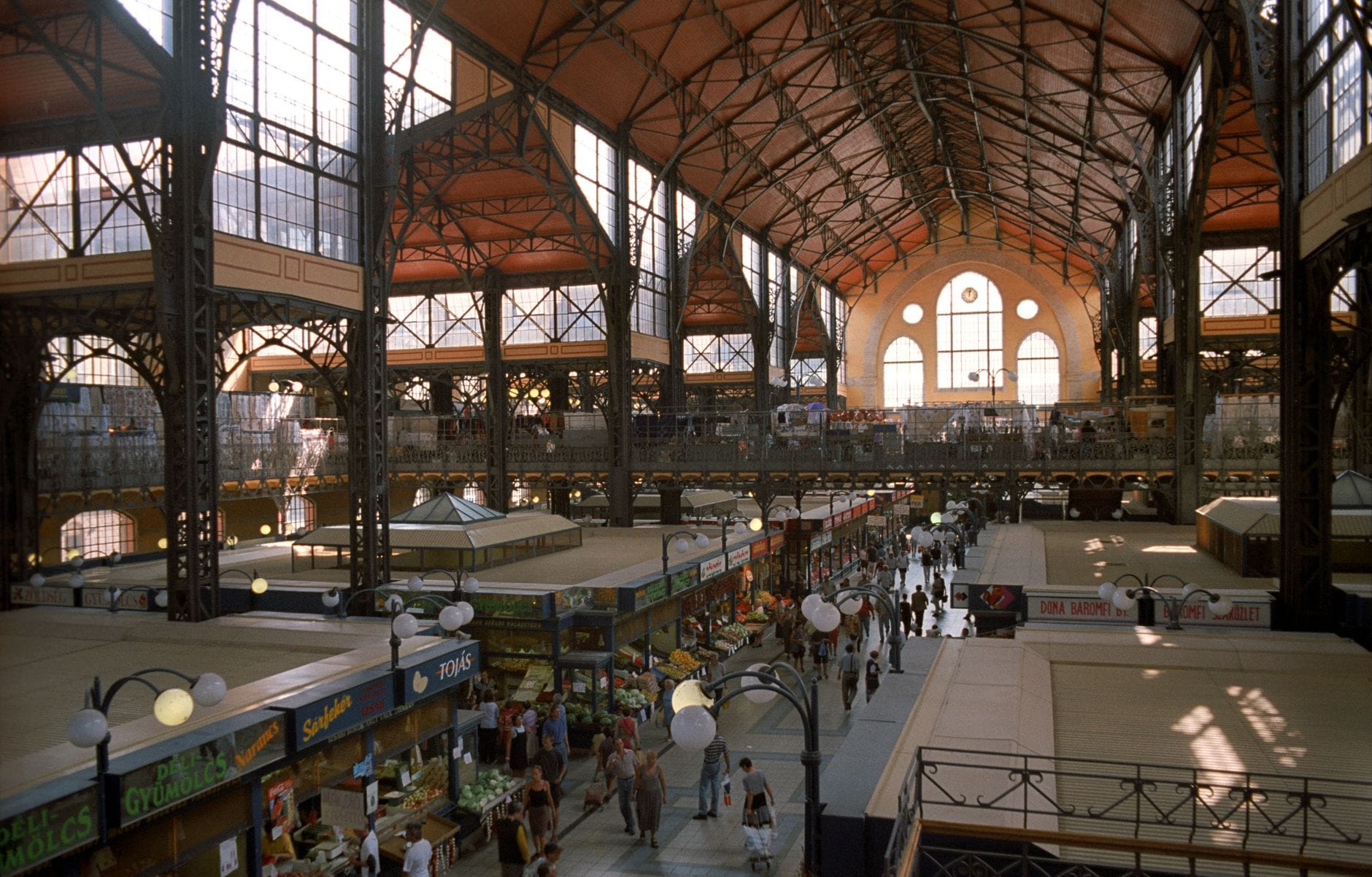 Weitwinklige Innenansicht der Großen Markthalle Budapest mit ihrem hohen Gewölbedach, Eisenarchitektur, Marktständen und Besuchern im Mittelgang.