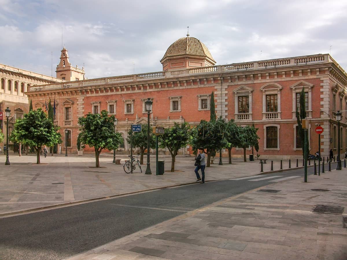 Il Centre Cultural La Nau a Valencia: la storica sede universitaria con la facciata in mattoni rossi, le finestre ad arco e la cupola iconica, vista dalla piazza antistante.