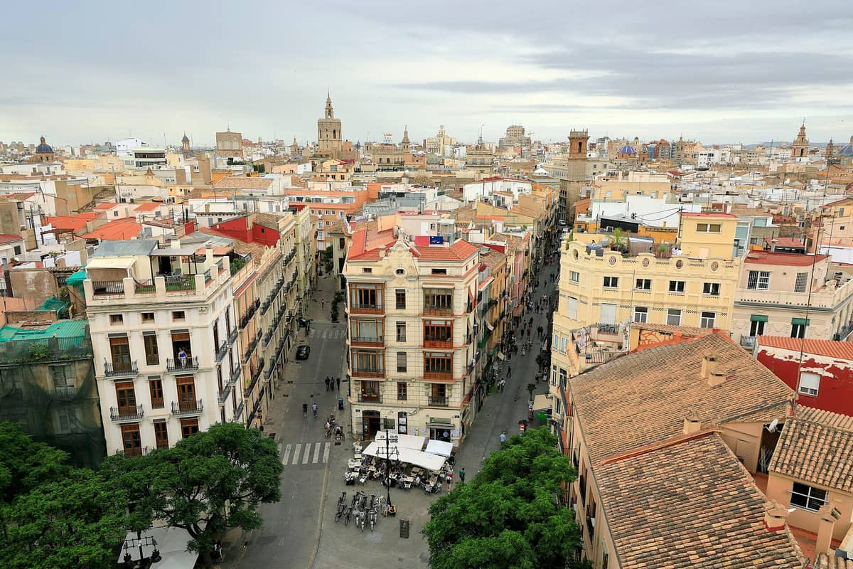 Ampia veduta aerea del Centro Histórico di Valencia con edifici storici, strade strette e animate, e torri di chiese tra cui la cattedrale e le torri delle porte medievali visibili nel panorama urbano.