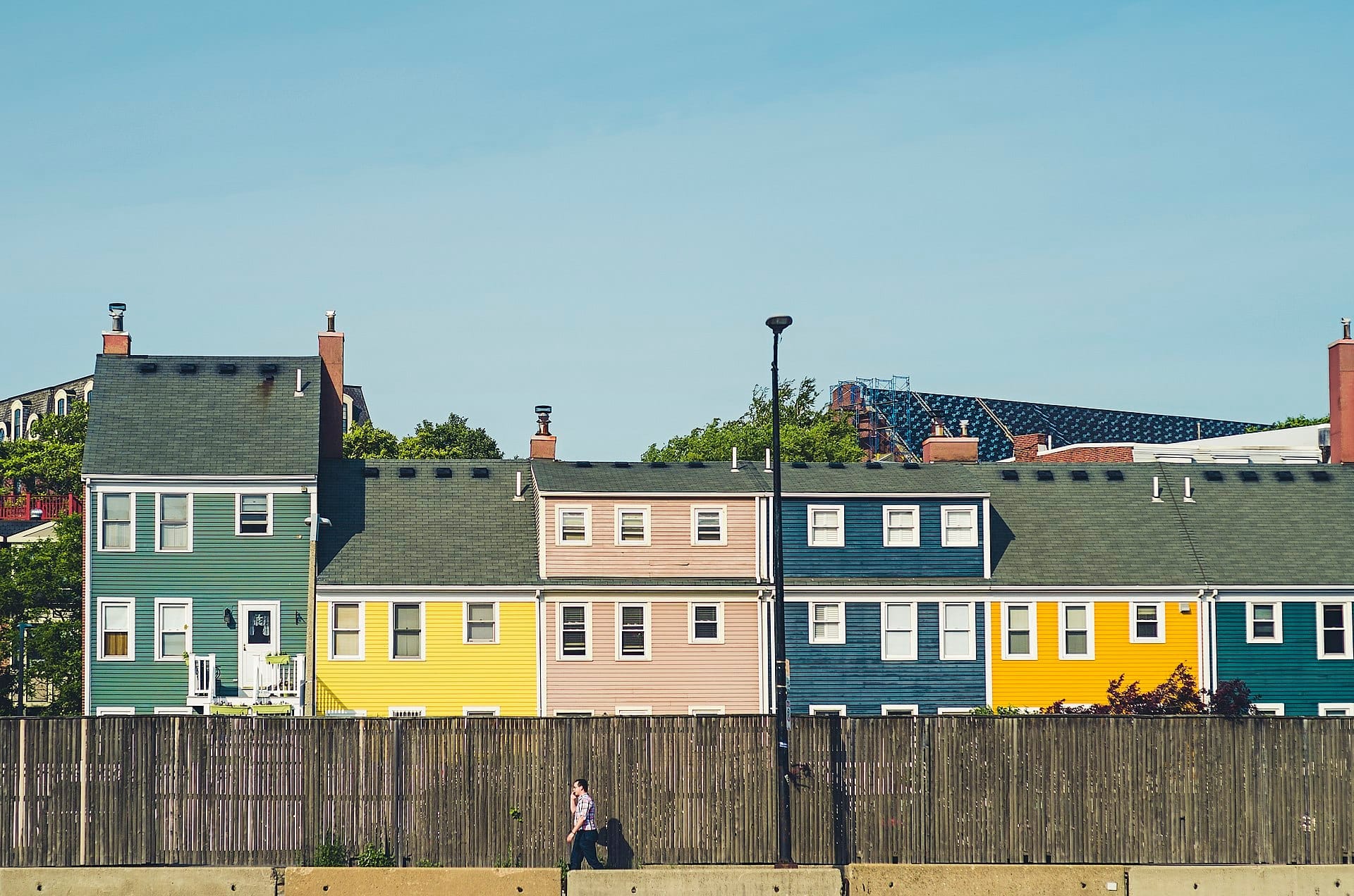 แถวบ้านทาวน์เฮาส์ประวัติศาสตร์หลากสีสันใน Charlestown, Boston มองเห็นด้านหลังรั้วไม้ในวันที่แดดจ้าและท้องฟ้าแจ่มใส