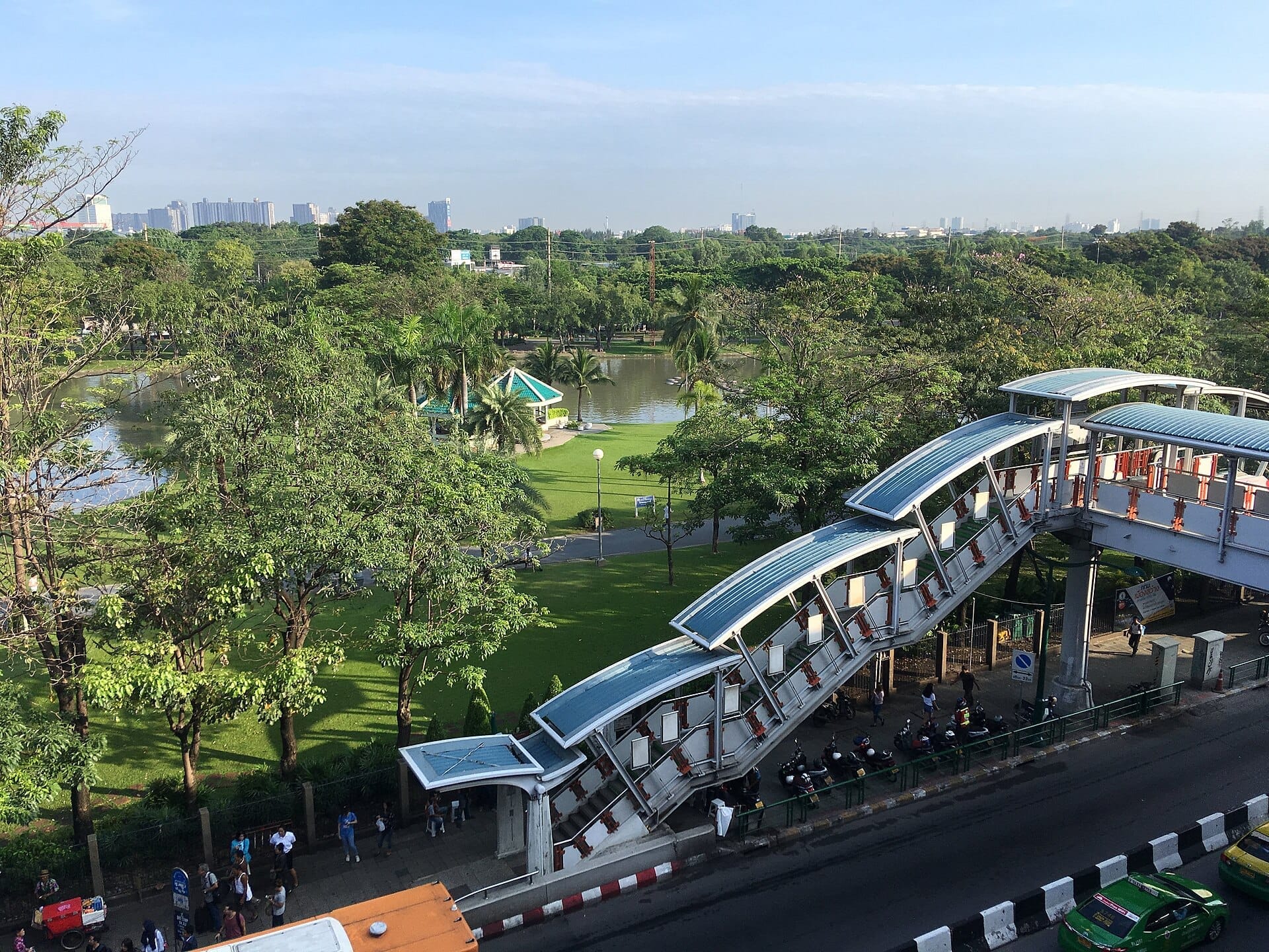 Prato verde aperto con alberi nel Chatuchak Park di Bangkok, zone ombreggiate e atmosfera da parco urbano tranquillo