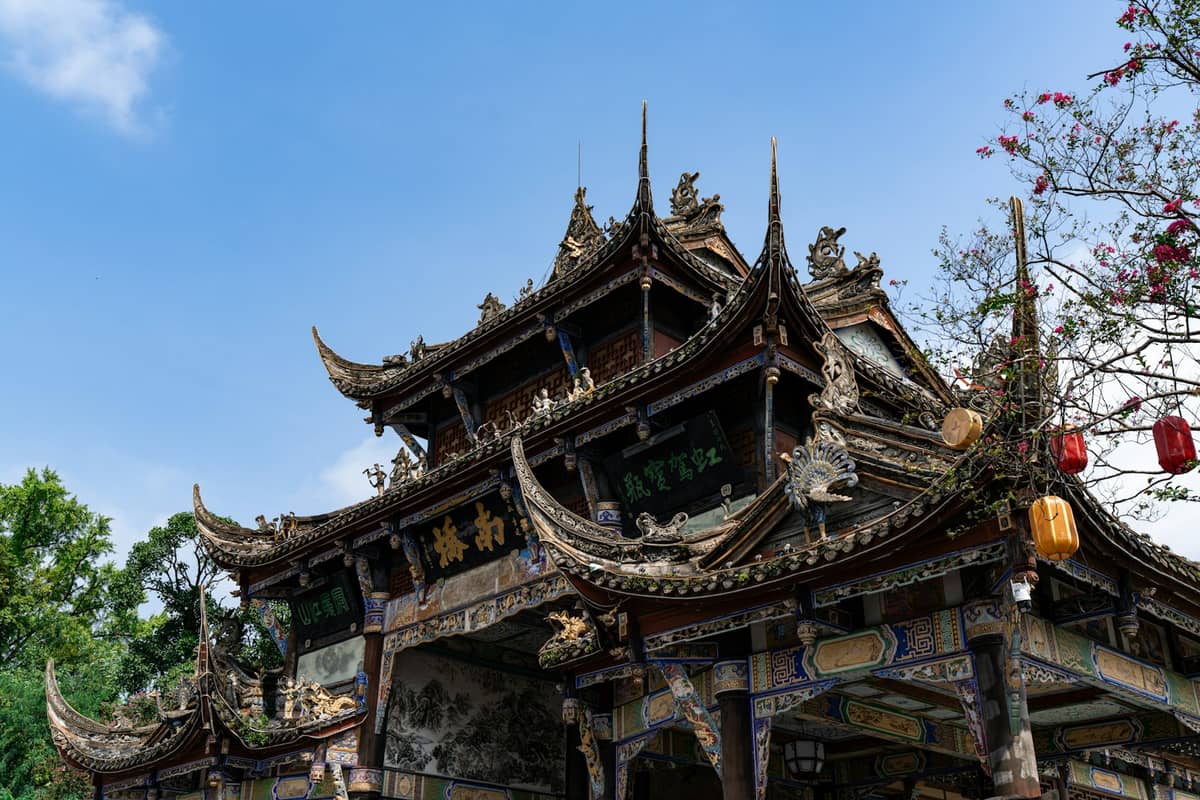 Edificio de templo chino tradicional en Chengdu con techo ornamentado y faroles rojos, al aire libre en un día despejado.