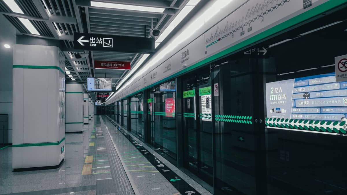 Innenraum einer modernen U-Bahn-Station mit grün-weißer Beschilderung, Bahnsteigtüren und klaren Wegweisern auf Chinesisch.