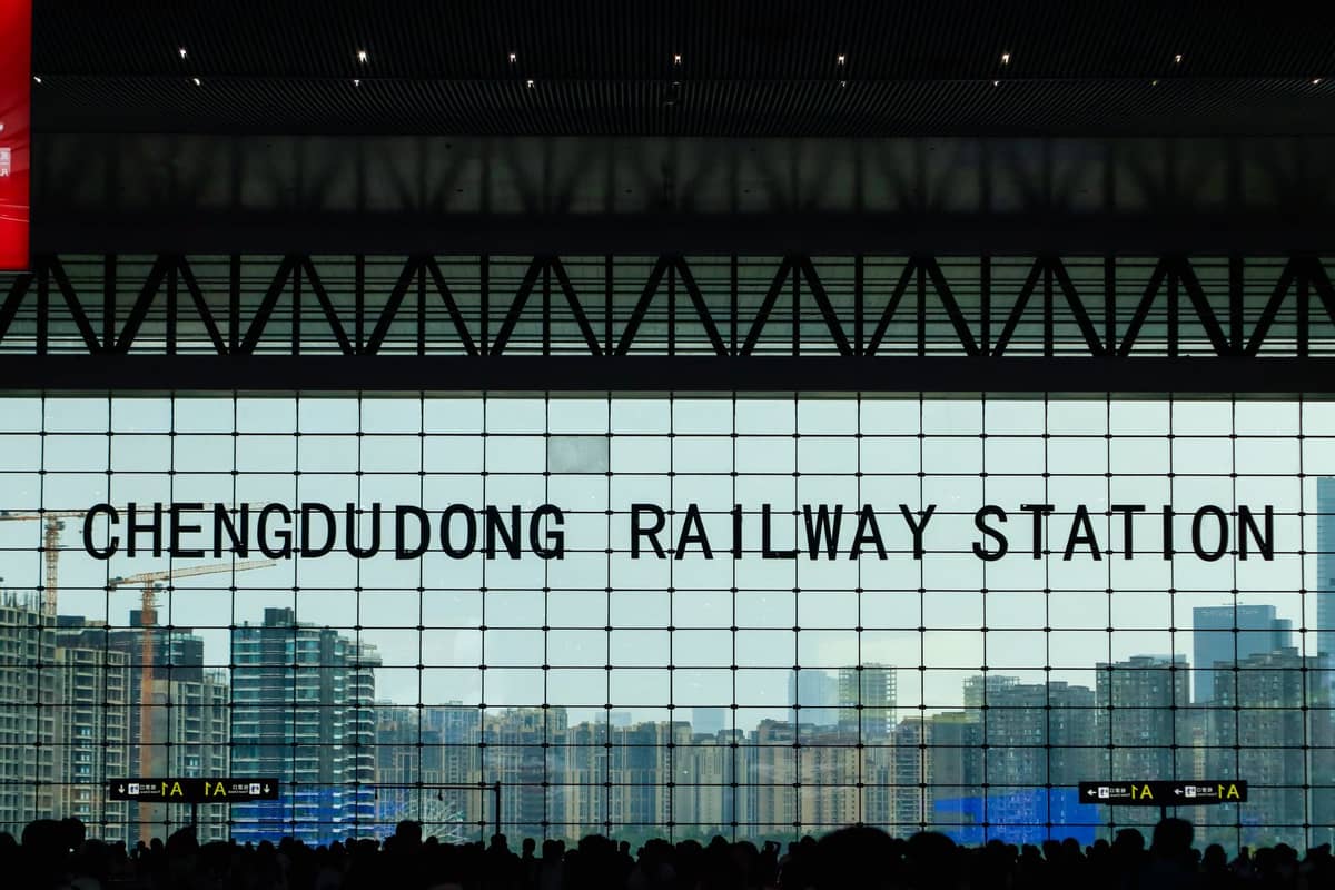 Ampio interno con folla in controluce e un'enorme vetrata con la scritta Chengdudong Railway Station, il principale hub per i viaggi tra Chengdu e Chongqing.