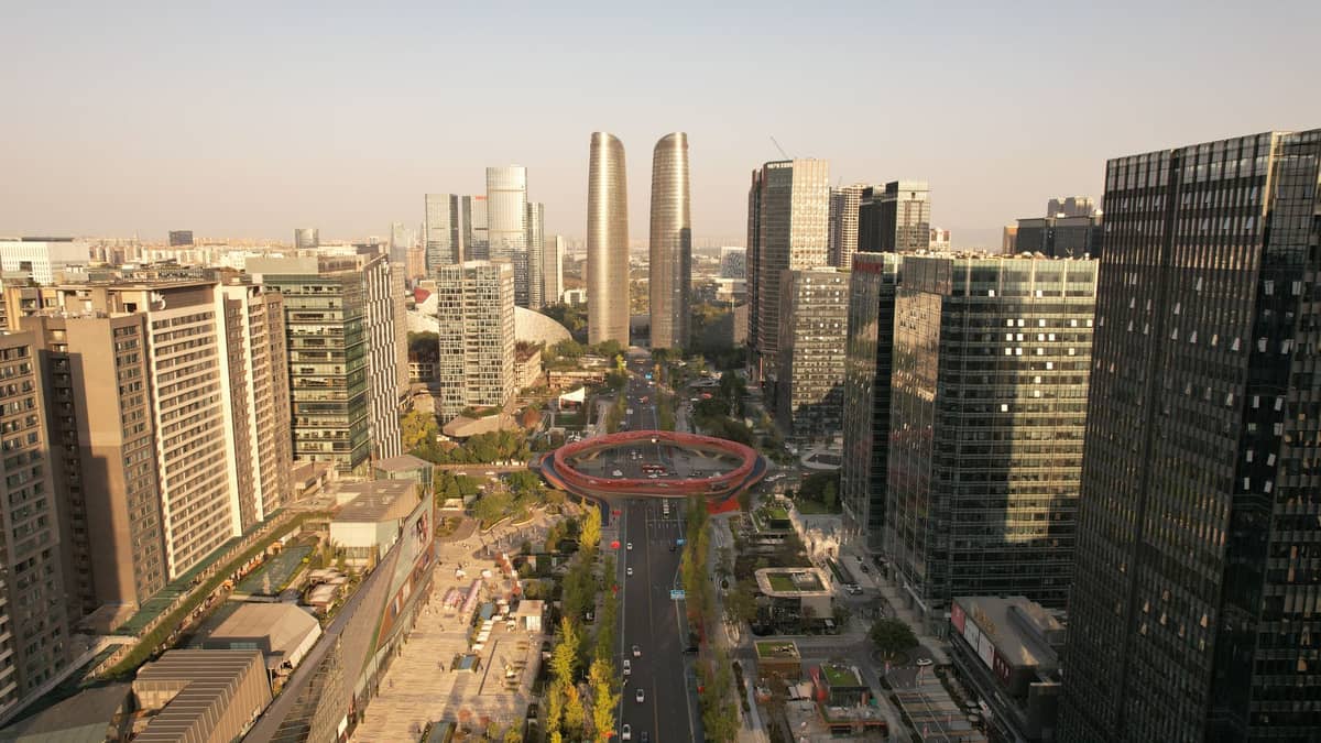 Weitläufige Luftaufnahme der modernen Skyline von Chengdu mit Hochhäusern und dem markanten kreisförmigen roten Fußgängerüberweg in der Mitte.