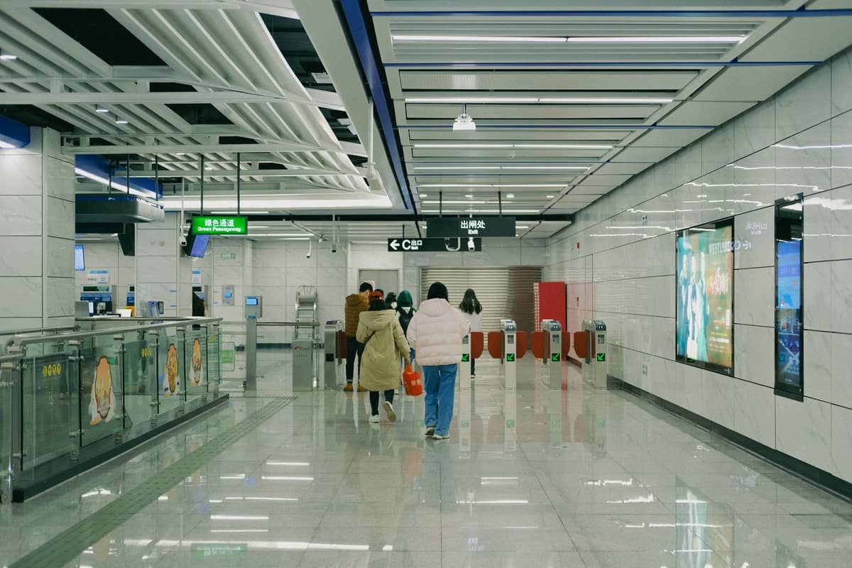Modernes, sauberes U-Bahnhof-Interieur in China mit Familien und Reisenden, die sich unter klarer Beschilderung den Ticketschranken nähern.