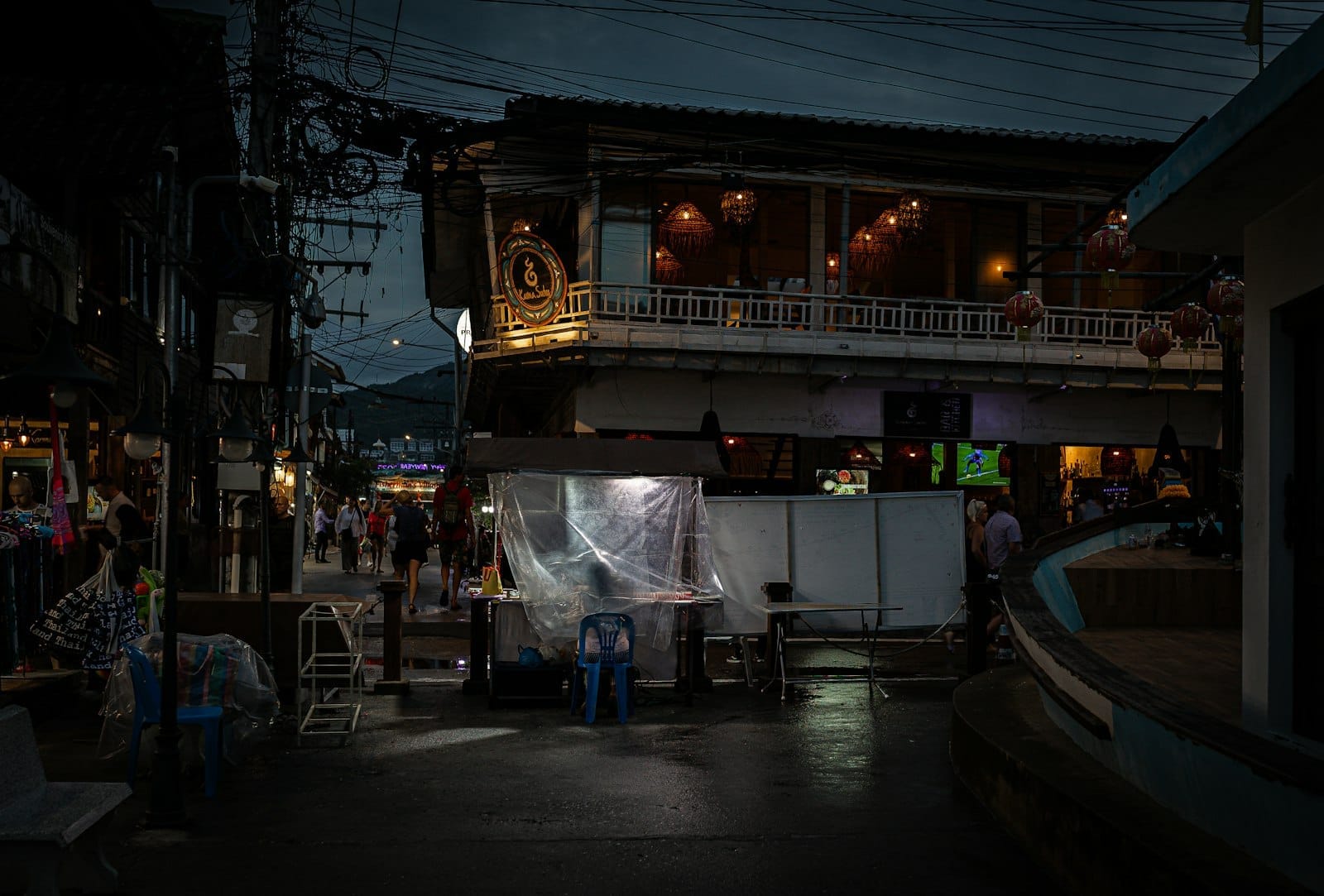 Escena callejera de Chiang Mai al atardecer con un animado edificio con linternas, peatones y una atmósfera nocturna bulliciosa e íntima.