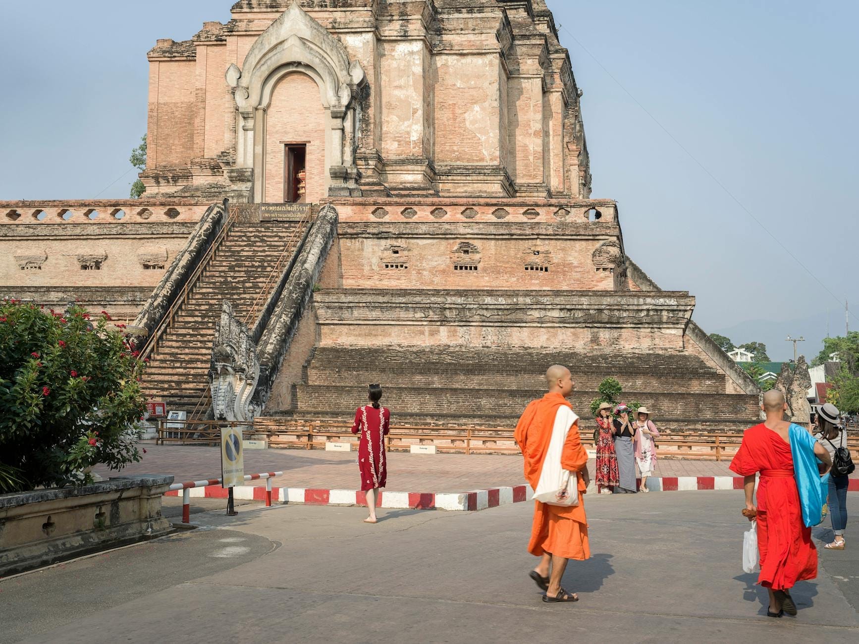 Các nhà sư và du khách đi bộ gần Wat Chedi Luang, một bảo tháp gạch lịch sử và địa điểm chùa nổi tiếng tại Chiang Mai