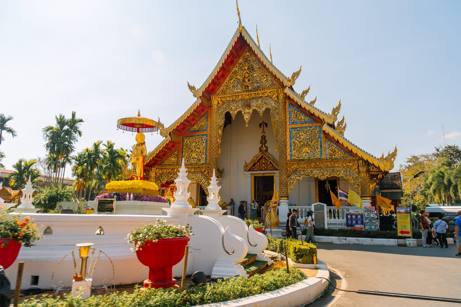 Một ngôi chùa Phật giáo mạ vàng tuyệt đẹp tại Thành phố Cổ Chiang Mai, với những trang trí cầu kỳ, tượng thờ và du khách tại lối vào dưới ánh sáng ban ngày rực rỡ.