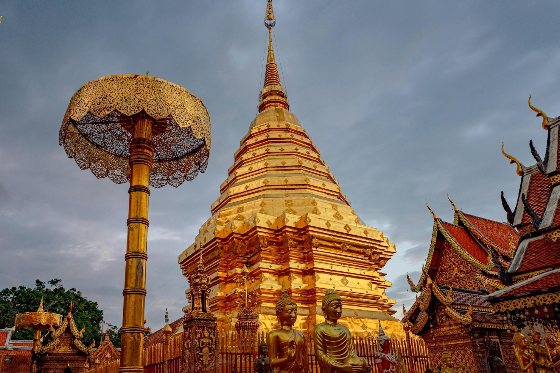 Pagoda dorada y estatuas en el templo Wat Phra That Doi Suthep en Chiang Mai bajo un cielo nublado
