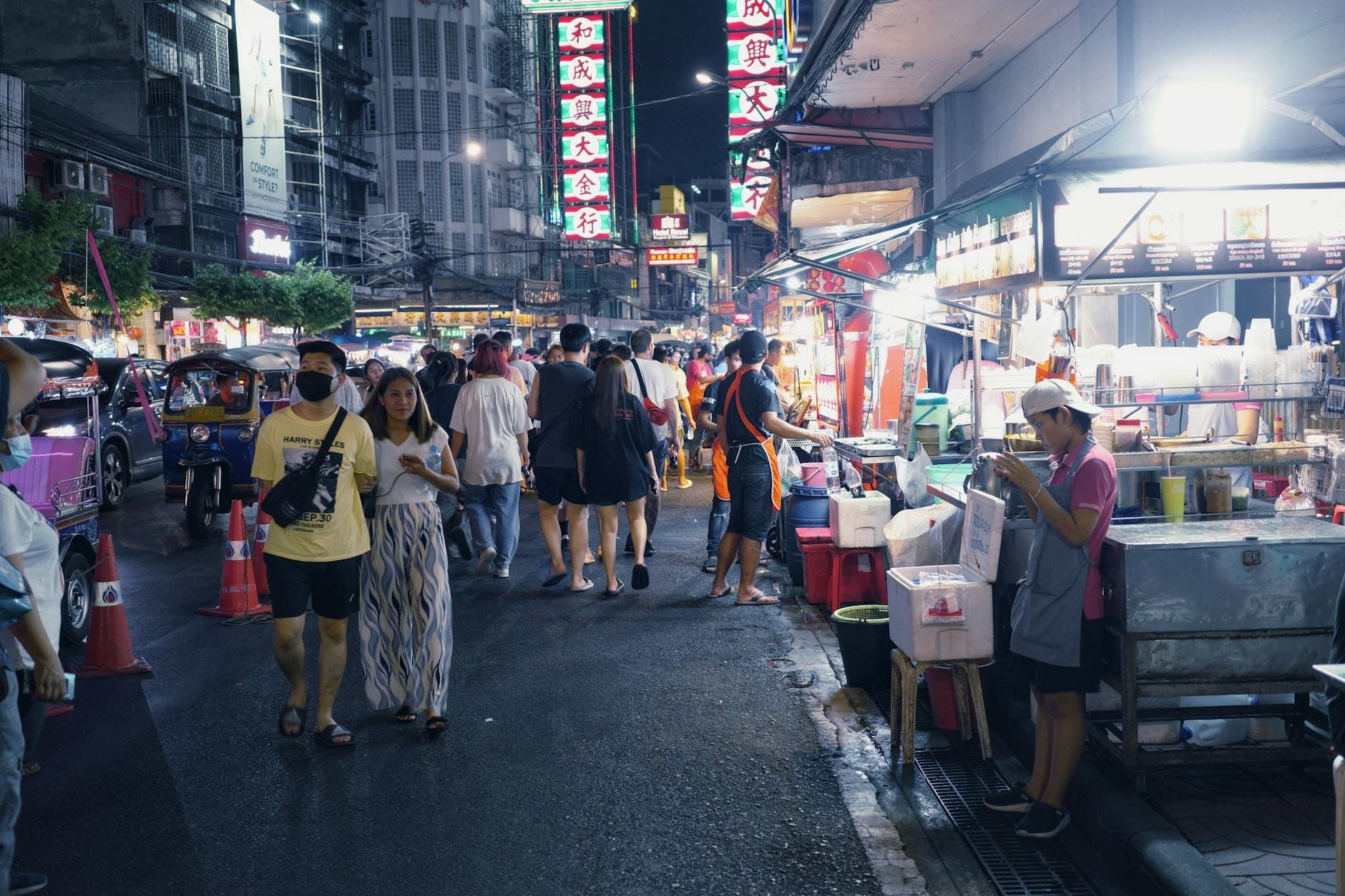 Cảnh chợ đêm nhộn nhịp với các gia đình và trẻ em đi dạo qua các quầy hàng ăn, đèn neon và người bán hàng rong ở Chiang Mai.