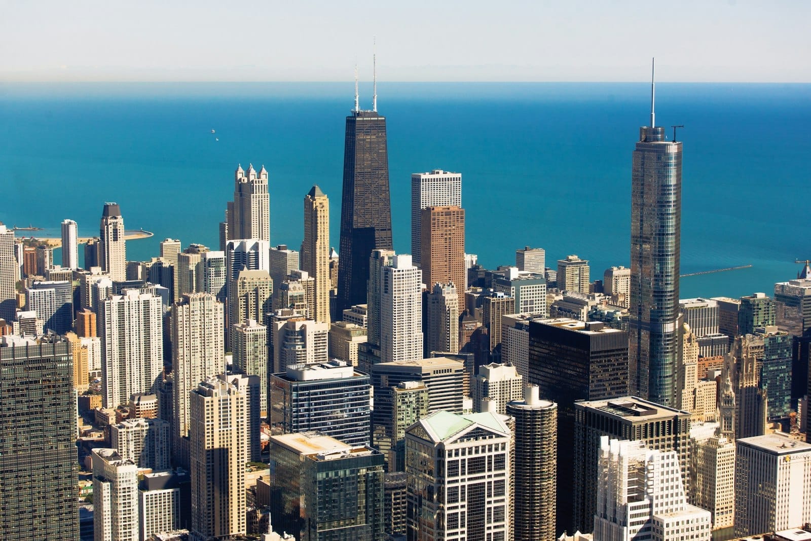 Vista aérea do icônico skyline do centro de Chicago com arranha-céus e o Lago Michigan ao fundo em um dia ensolarado.