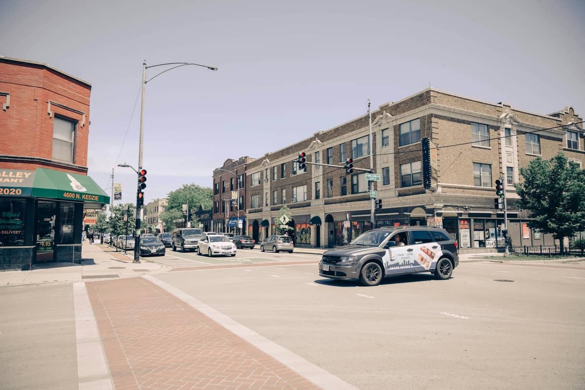 Straßenecke in Chicago mit historischen Backsteingebäuden, Geschäften und Verkehr, die die klassische Atmosphäre eines Stadtviertels einfängt.