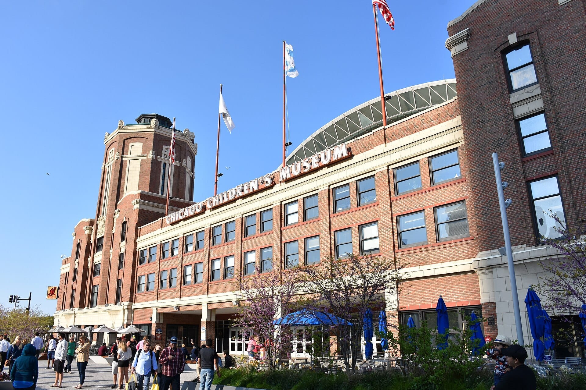 L'esterno del Chicago Children's Museum al Navy Pier, con facciata in mattoni rossi, bandiere e famiglie riunite fuori in una giornata di sole.