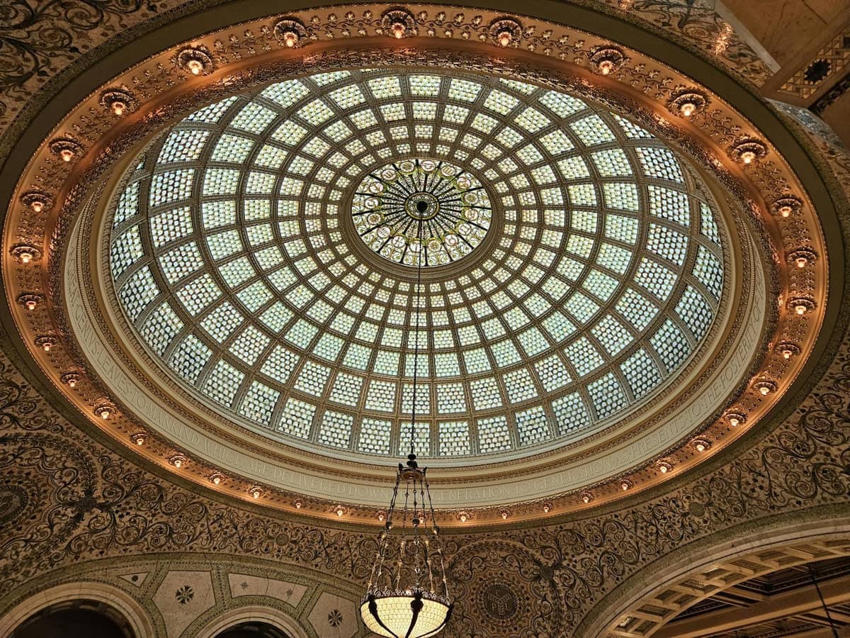 Verzierte Buntglasdachkuppel und Kronleuchter in einem historischen Gebäude in Chicago, mit aufwendigen Details an der umgebenden Architektur.