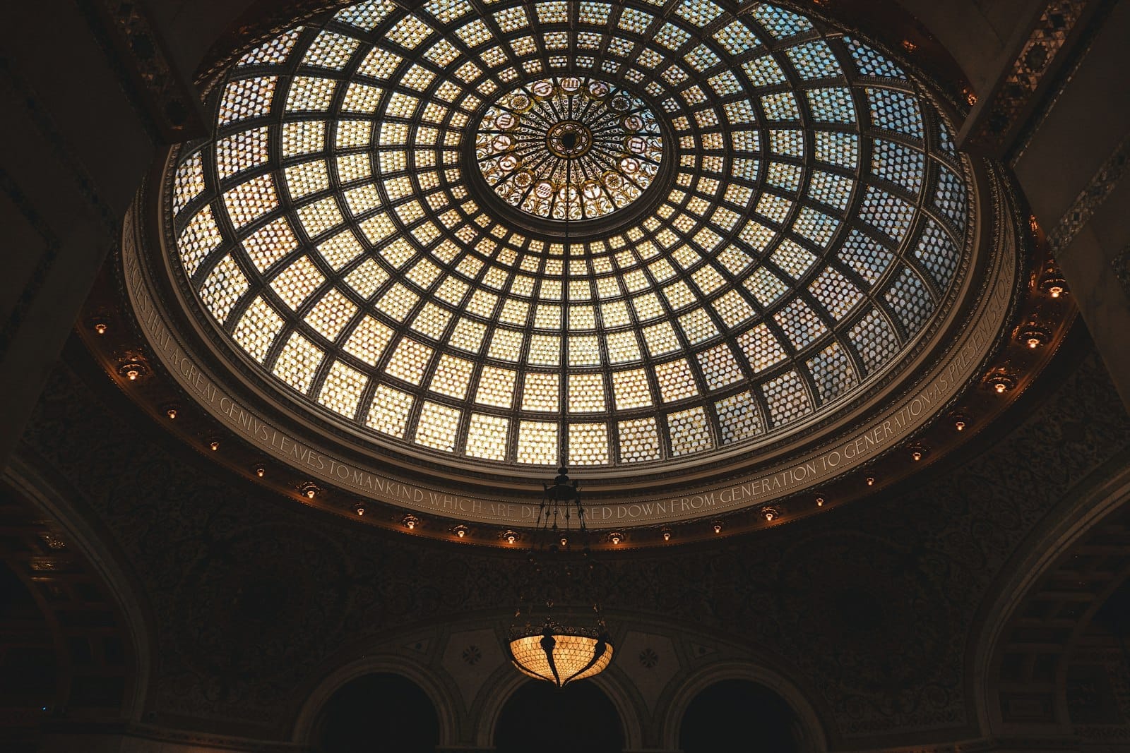 Vista dell'interno del Chicago Cultural Center con la grande cupola in vetro colorato Tiffany, i suoi intricati motivi geometrici e un lampadario sospeso, immersa nell'elegante architettura Beaux-Arts.