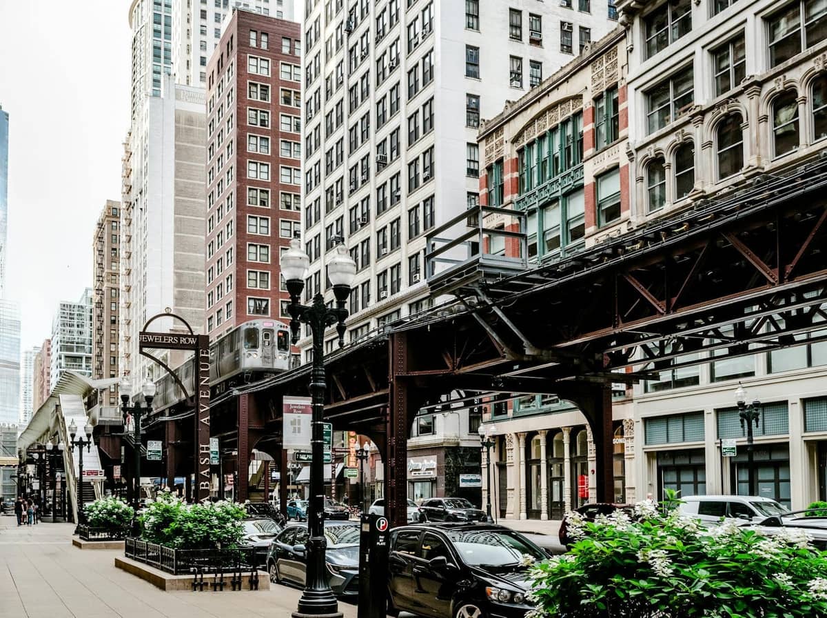 Straßenszene in Chicago mit Hochbahngleisen, historischen Gebäuden und geparkten Autos im Restaurant-Viertel der Innenstadt.